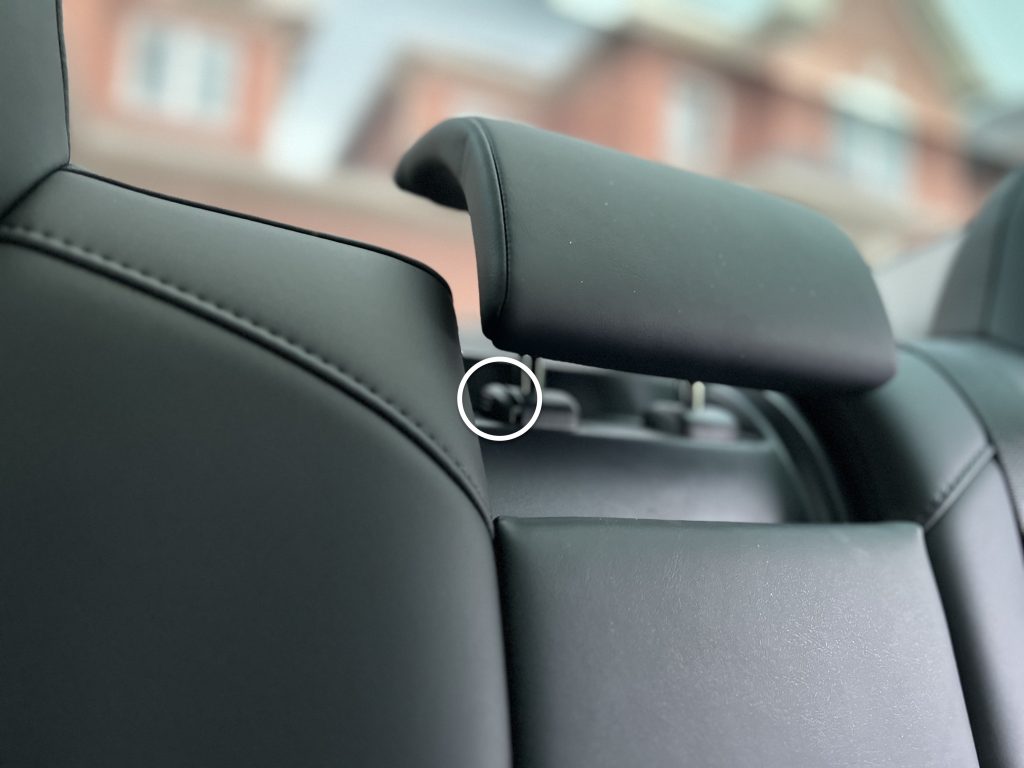 Button at the Base of the Outer Post of the Rear Centre Head Support used to remove it in a Tesla Model 3 or Model Y.