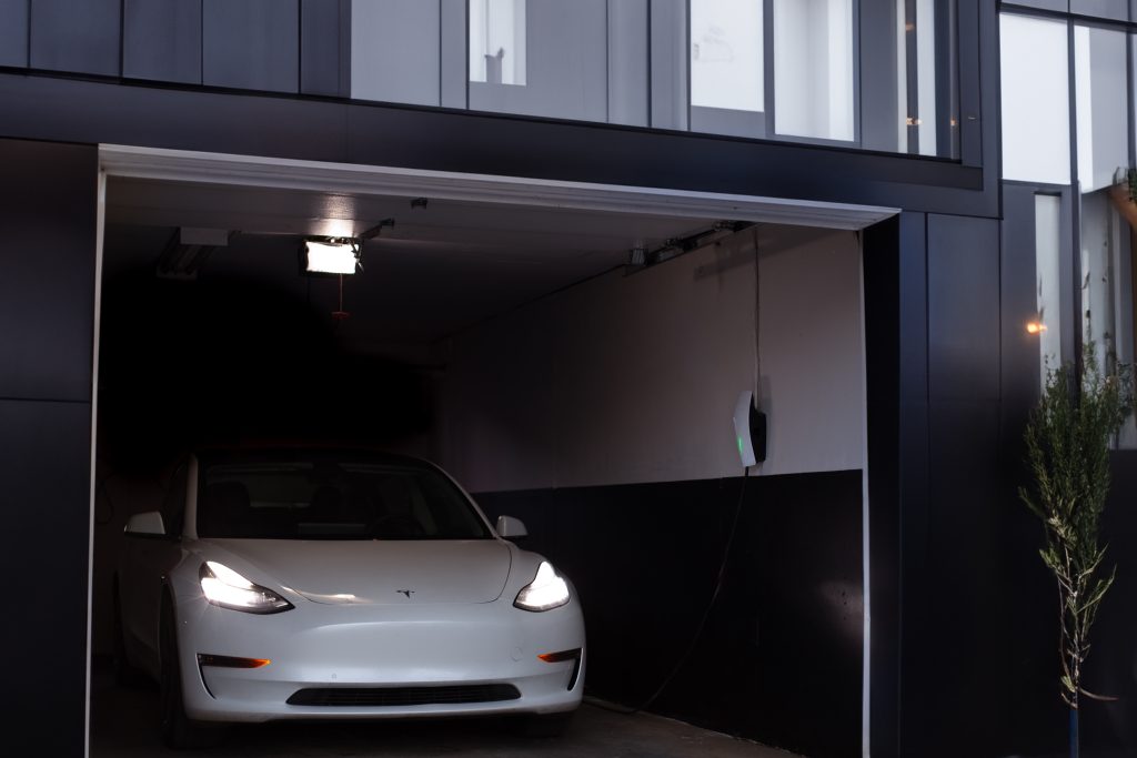 Pearl White Tesla Model 3 with a Tesla Wall Connector on the Wall