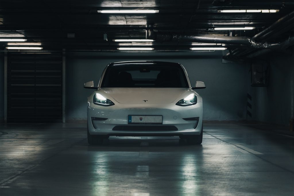 Pearl White Tesla Model 3 with Headlights on