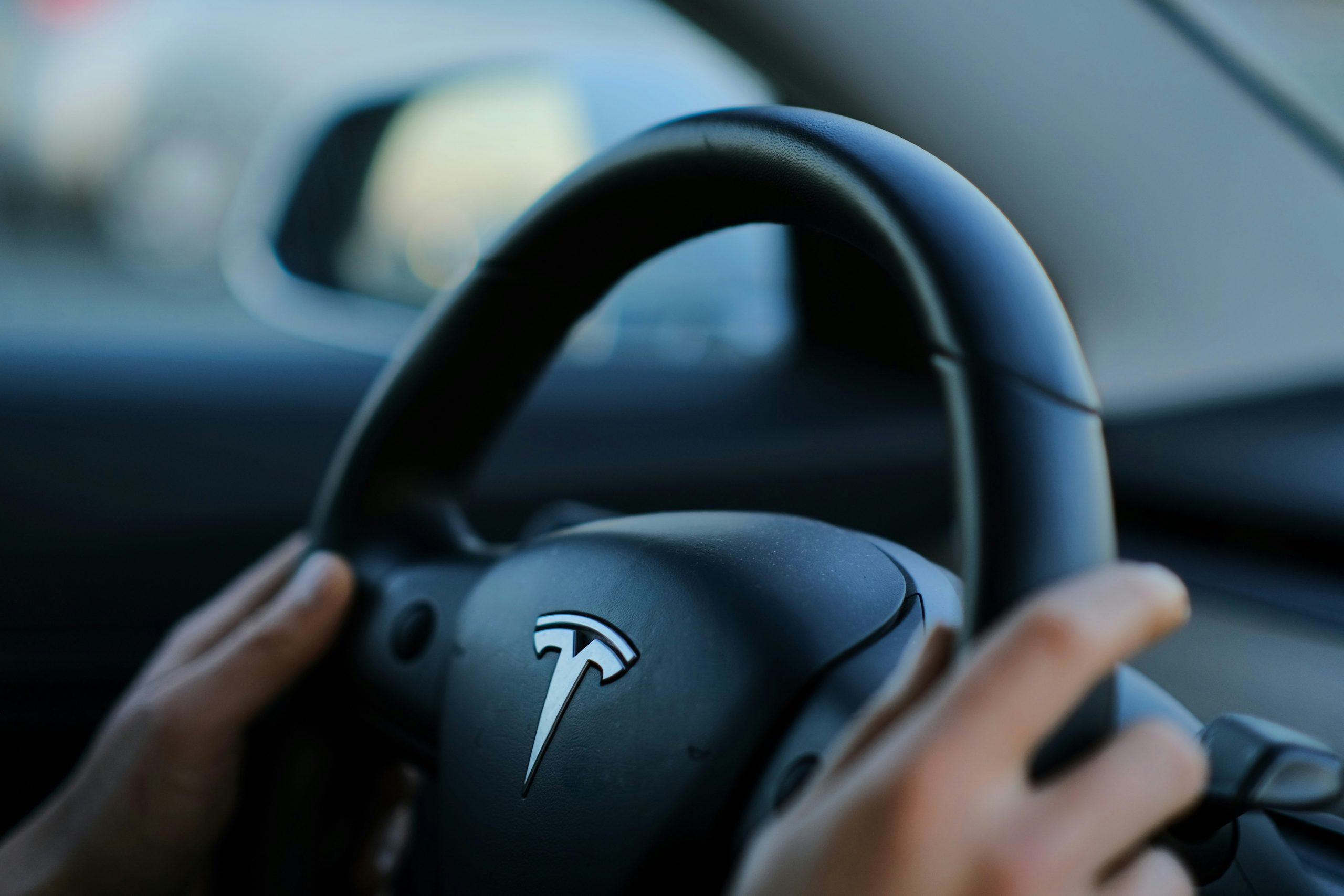 Person's Hands on the Steering Wheel of a Tesla